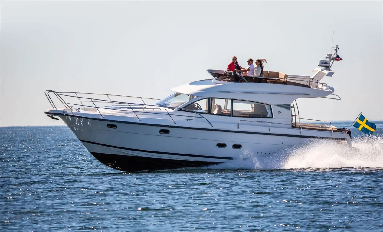 Luxury motorboat with three passengers cruising on calm water, featuring a Swedish flag waving in the breeze.